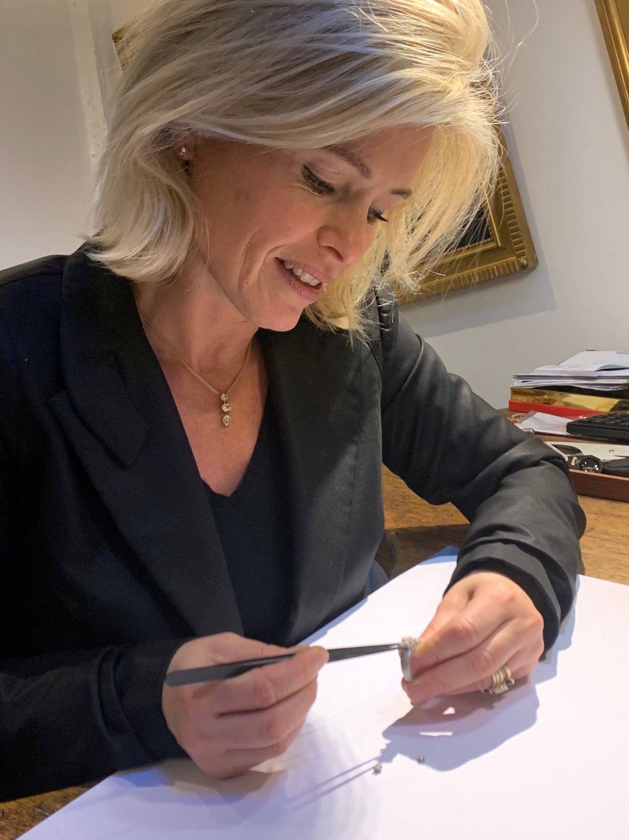 Woman writing on a piece of paper with a pen in an indoor setting.